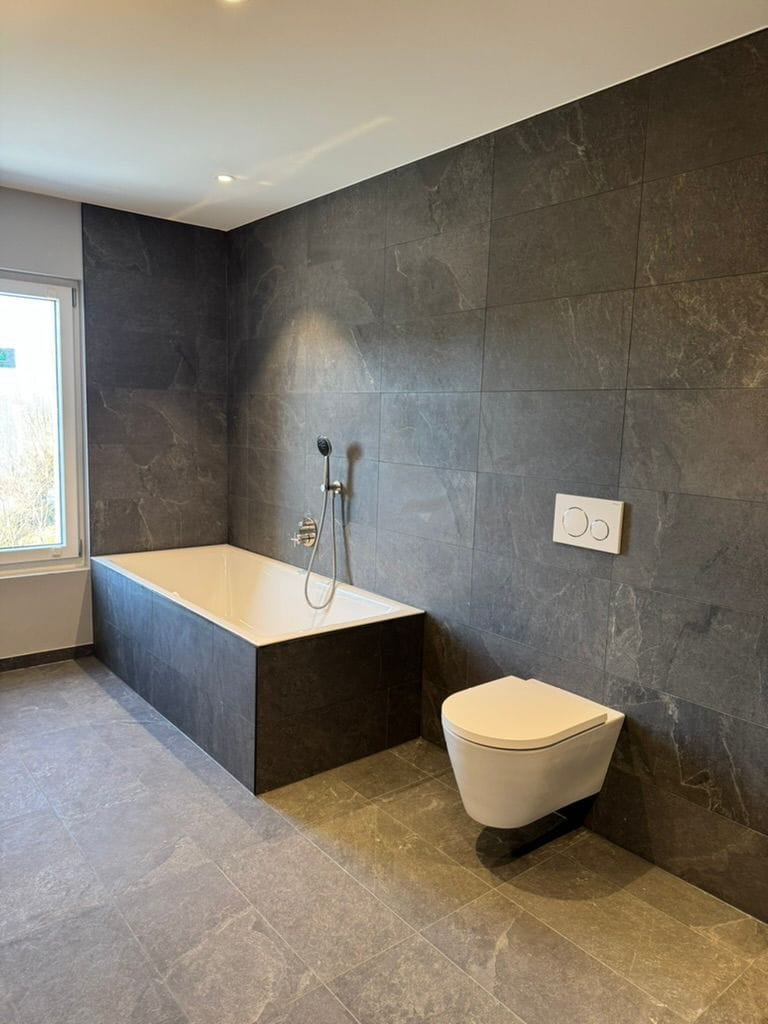 Vue d'ensemble de la salle de bain avec baignoire et WC suspendu