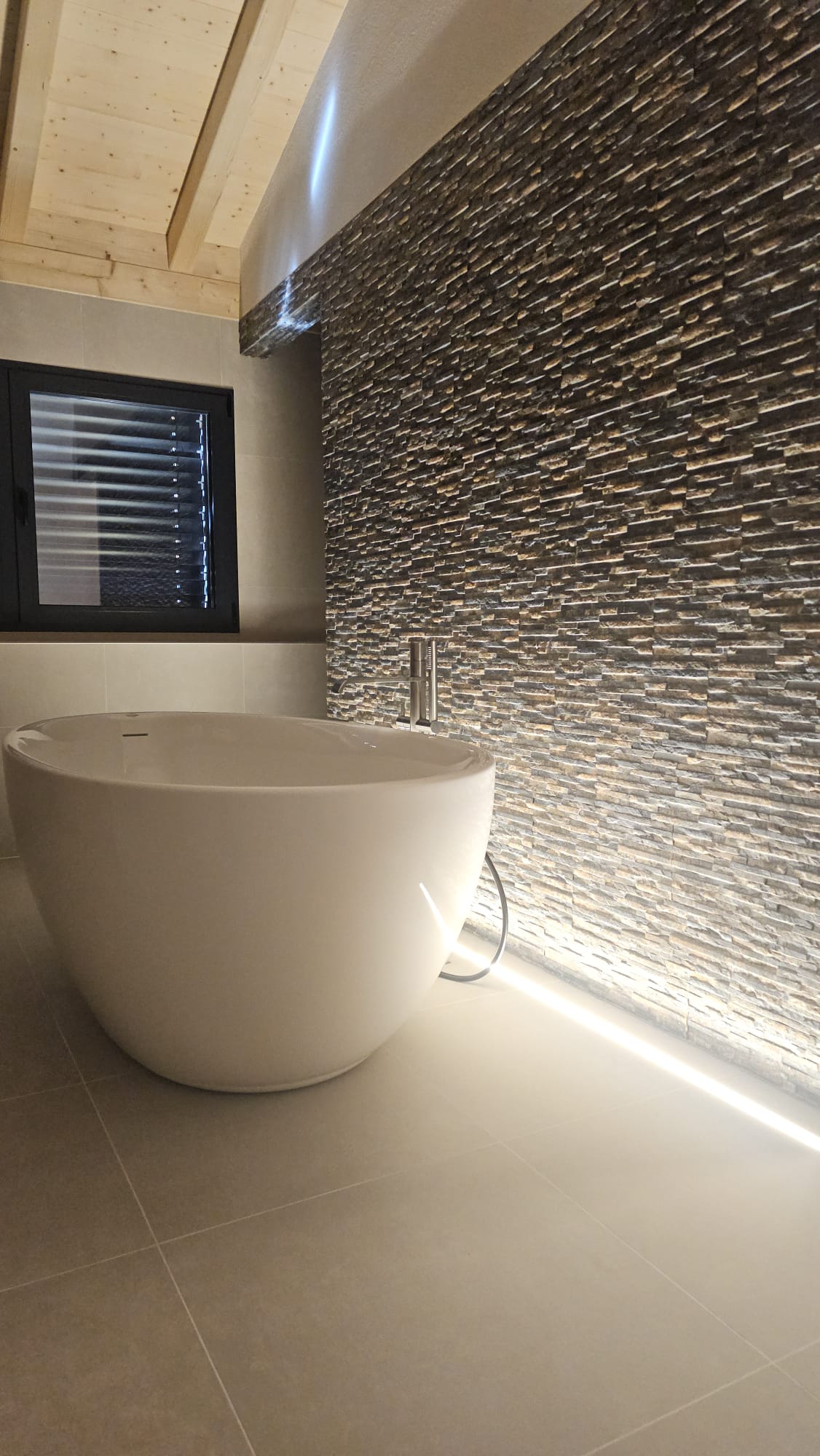 Salle de bain contemporaine avec baignoire îlot et mur minéral rétroéclairé