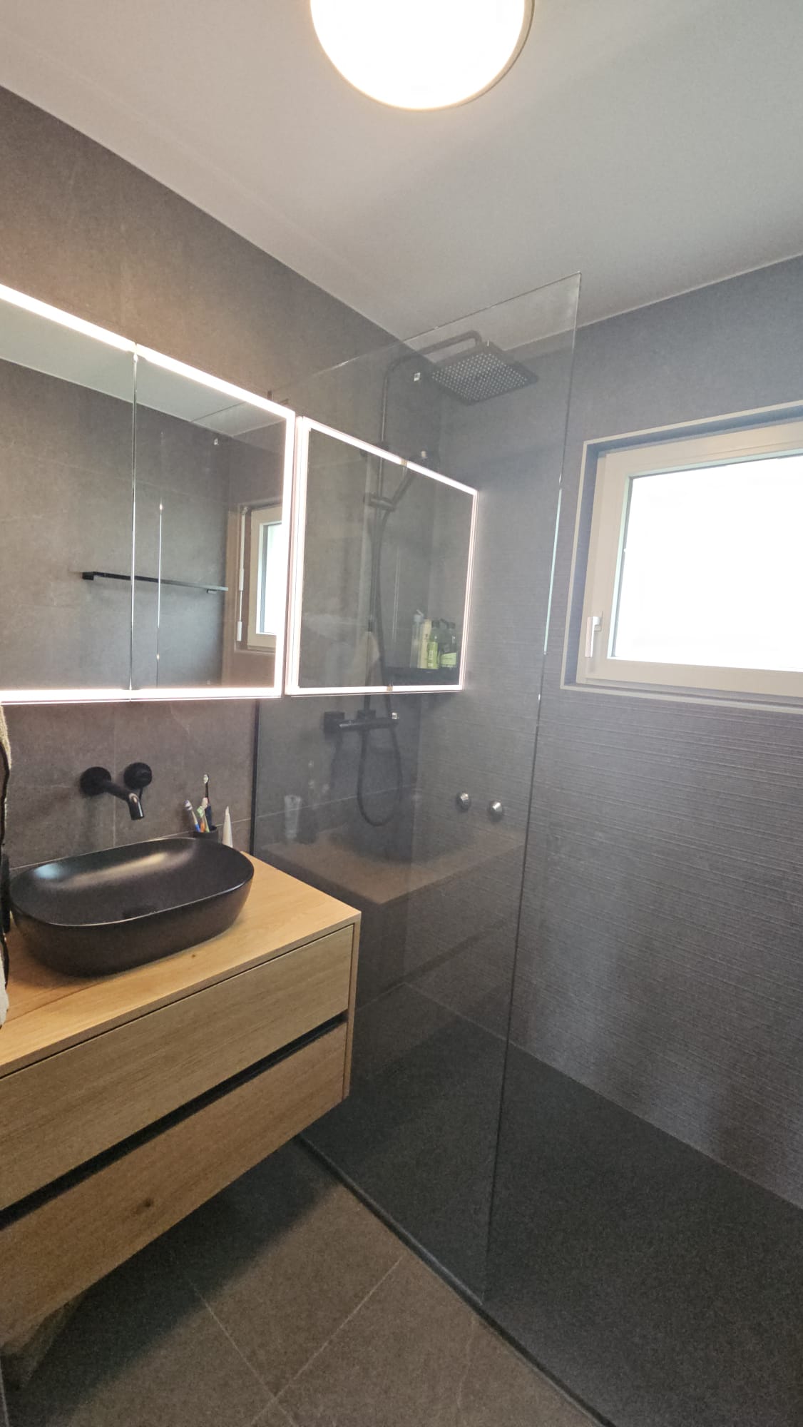 Salle de bain rénovée avec meuble vasque en bois et miroir lumineux